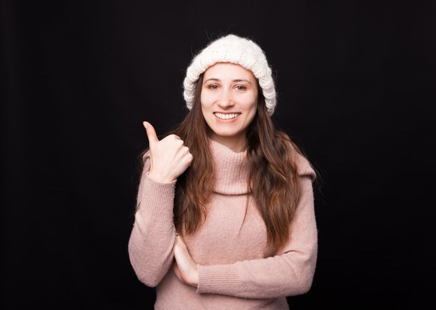 De vrij jonge vrouw die duim toont lacht naar de camera.