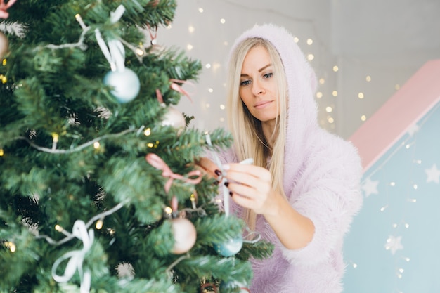 De vrij jonge vrouw met blond haar verfraait een kerstboom