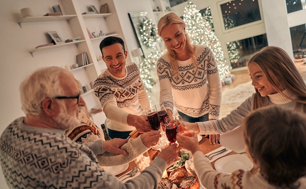 De vrolijke familie rammelglazen boven de kersttafel