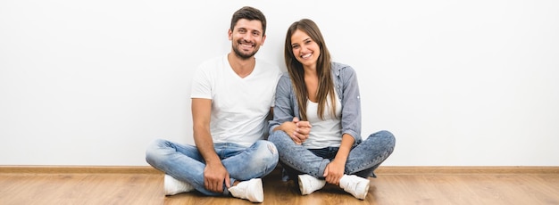 De vrolijke man en vrouw zitten bij de lege muur