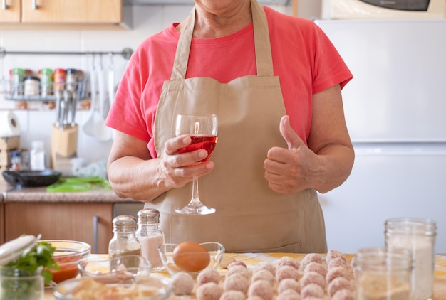 De vrouw beëindigde het bereiden van gehaktballen terwijl ze genoot van een glas wijn