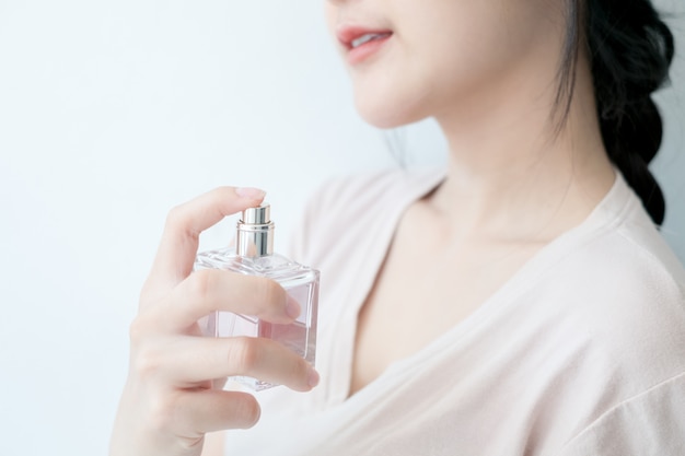 De vrouw bespuit parfum bij de hals.