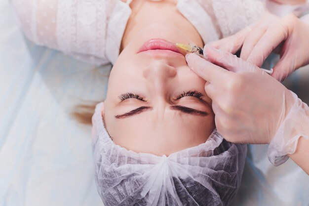 De vrouw die een injectie in haar lippen ontvangt, sluit omhoog.