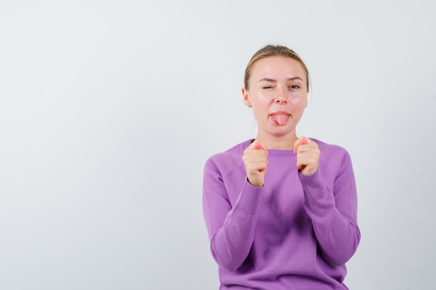 De vrouw die haar tong uitsteekt vertoont een handgebaar op een witte achtergrond