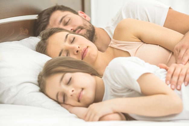 De vrouw die in de buurt van het gezin op het comfortabele bed slaapt