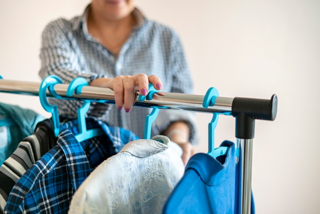 De vrouw die thuis de kleren op de hanger doorzoekt en de juiste kiest