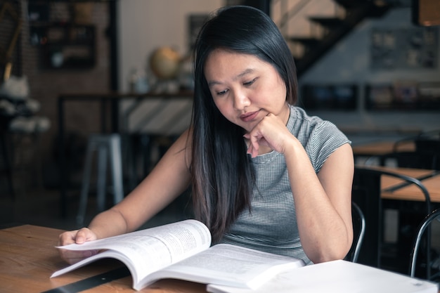 De vrouw die van Azië een boek in koffiewinkel leest