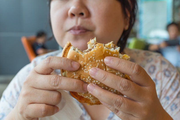 De vrouw die van Azië een hamburger eet