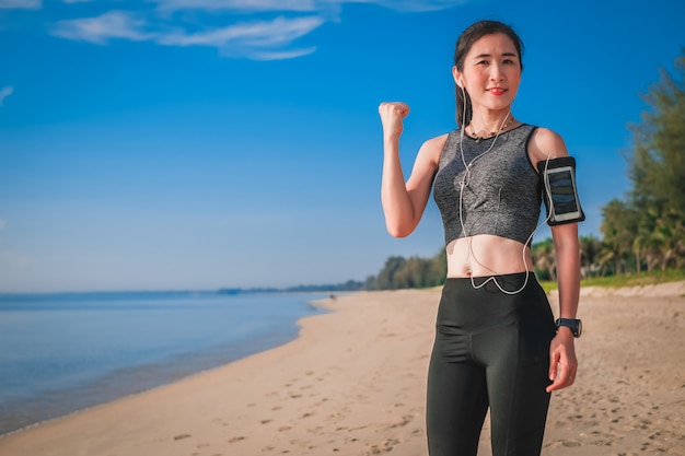 Foto de vrouw die van azië in sportwaren voor het uitoefenen genieten en op het strand lopen.