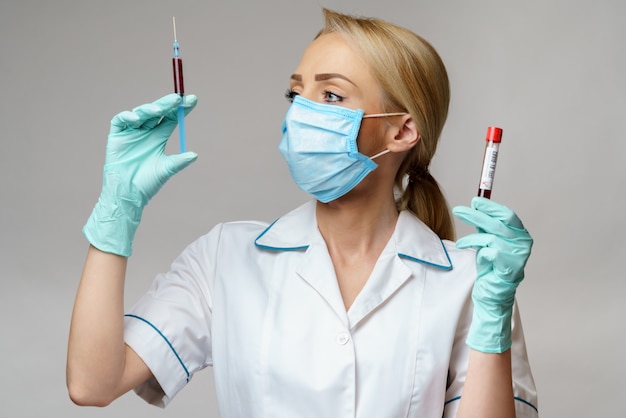 De vrouw die van de medische artsenverpleegster beschermend masker en handschoenen dragen