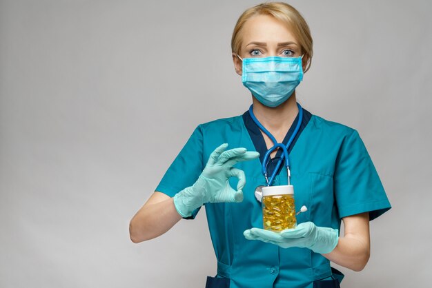 De vrouw die van de medische artsenverpleegster beschermend masker en rubber of latexhandschoenen dragen - het houden kan van pillen