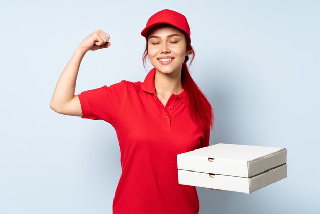 De vrouw die van de pizzakoerier een pizza over geïsoleerde muur houdt die sterk gebaar doet