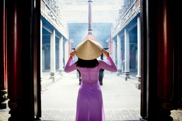 Foto de vrouw die van vietnam ao dai-cultuur traditioneel bij oude tempel in ho chi minh in vietnam dragen