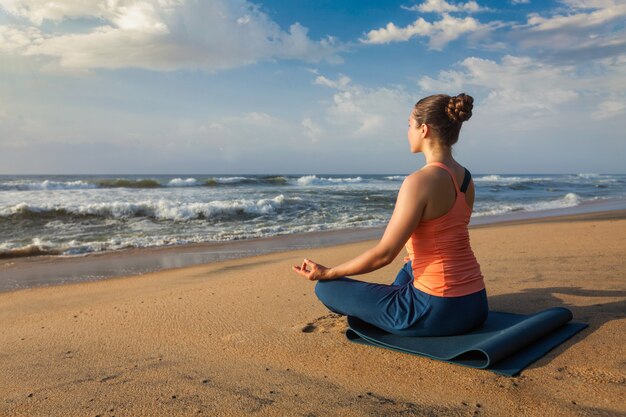 De vrouw die yoga Lotus doet stelt oudoors bij strand