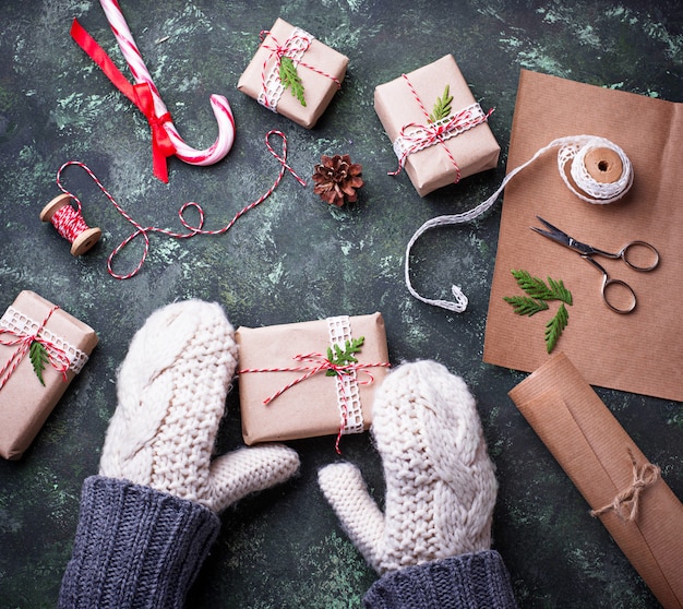 De vrouw dient vuisthandschoenen in verpakkingsdozen met de giften van Kerstmis voorstelt. Bovenaanzicht