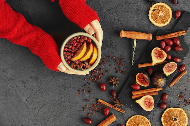 De vrouw dient warme sweater in houdend een kop glühwein