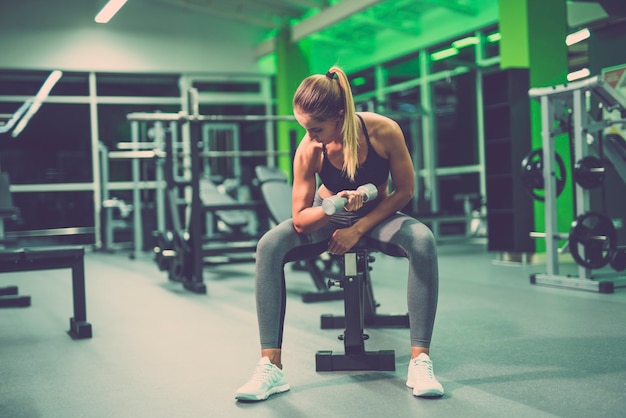 De vrouw doet oefening met een halter in de fitnessclub