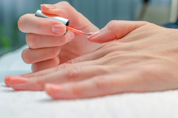 De vrouw doet zelf de manicure. Vrouwelijke handen met manicurehulpmiddelen. Nagelverzorging concept.