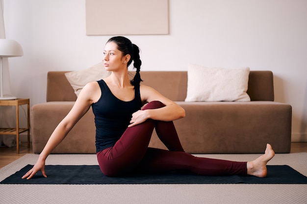 De vrouw doet zittende draai-oefeningen voor gezondheid en een steviger lichaam