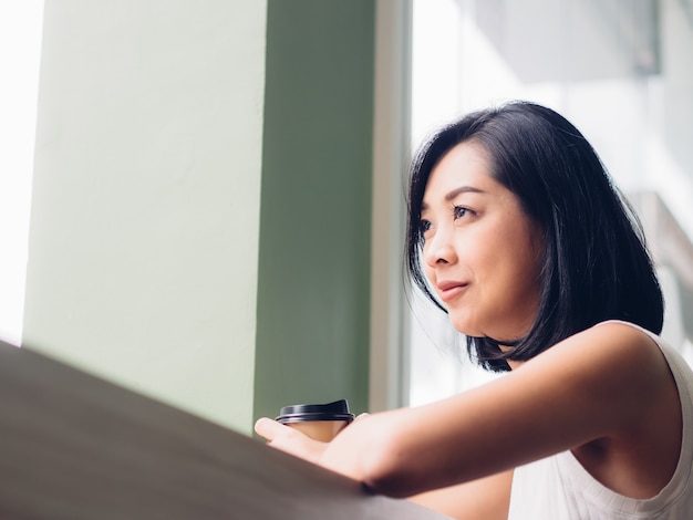 De vrouw drinkt hete kop van koffie in de koffie.