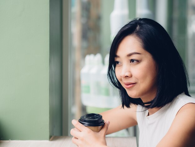 De vrouw drinkt hete kop van koffie in de koffie.