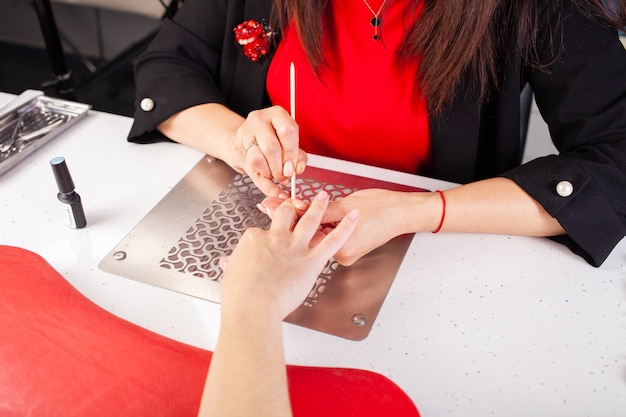 De vrouw duwt de nagelriem met een houten stok