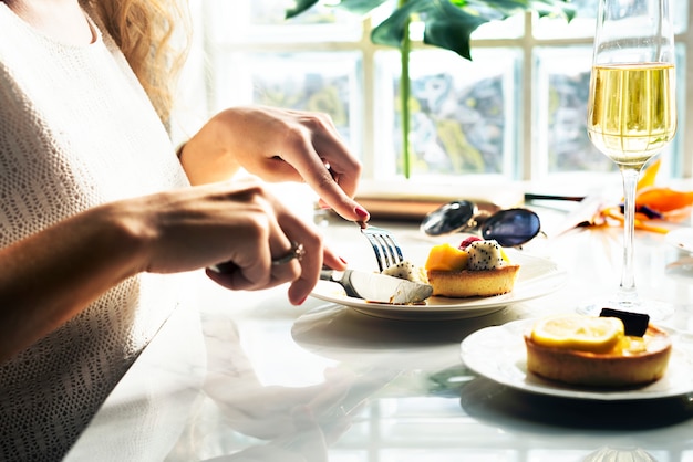 De vrouw eet gebakje bij het restaurant