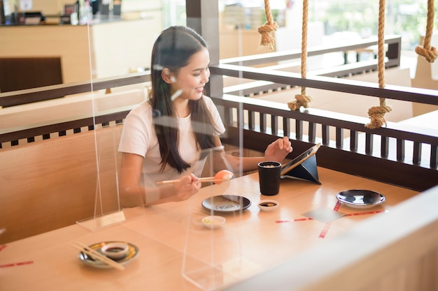 De vrouw eet in Restaurant met sociaal afstands protocol