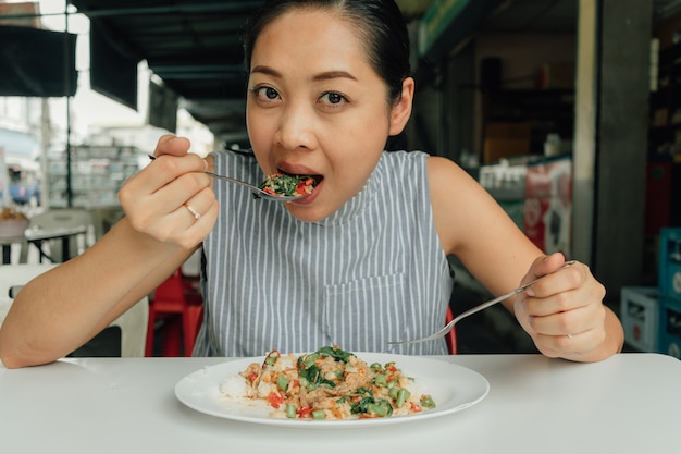 De vrouw eet thais rijst be * wegen-gebraden varkensvlees en basilicum.