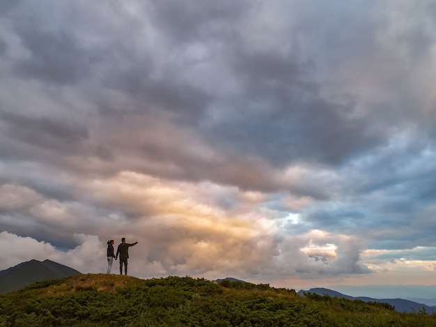 De vrouw en man die op de berg staan met een prachtig uitzicht