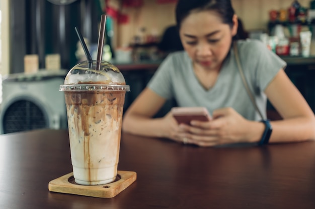 De vrouw gebruikt smartphone in het koffiecafé.