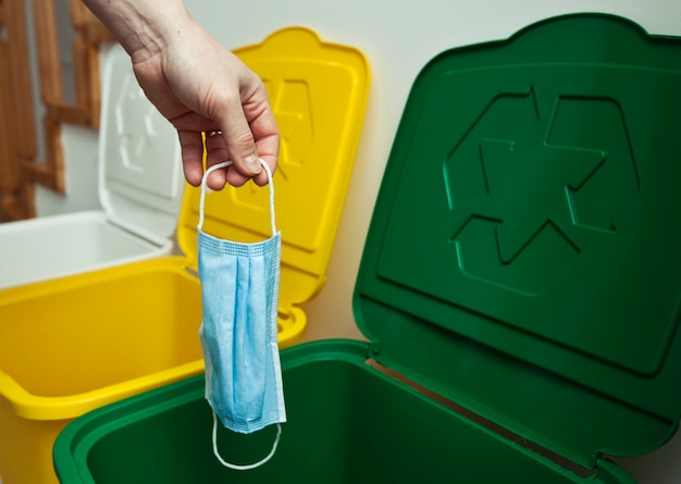 De vrouw gooit het medische masker in een van de drie vuilnisbakken