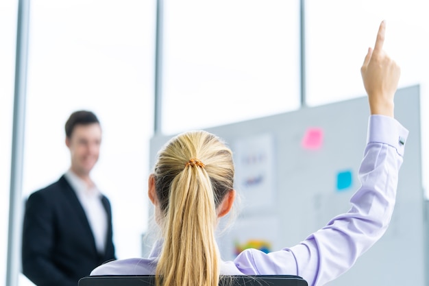 Foto de vrouw hief omhoog haar hand voor vraag in conferentievergadering op