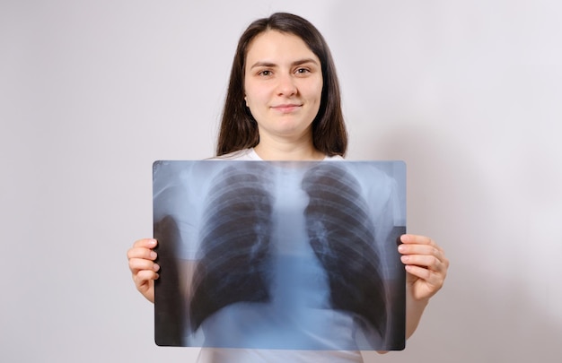 De vrouw houdt een röntgenfoto van haar longen vast op borsthoogte