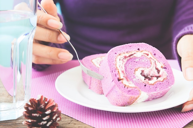 De vrouw in purple breit kleding etend de cake van het bosbessenbroodje