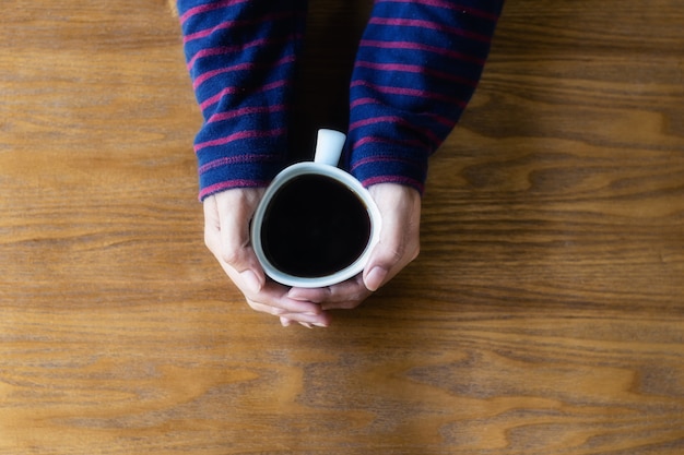 De vrouw is handen die kopkoffie, hoogste mening, hout houden