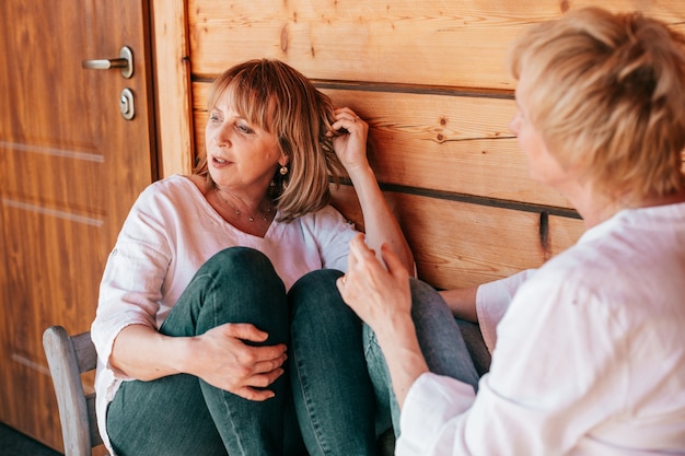 De vrouw is in gedachten verzonken en kijkt opzij terwijl haar vriendin, van achteren gezien, haar mening uitspreekt