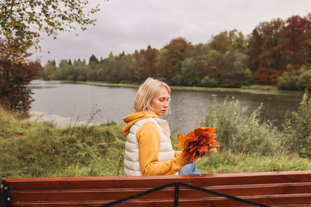 De vrouw is in het herfstpark. Herfstsfeer, schilderachtig uitzicht op de rivier