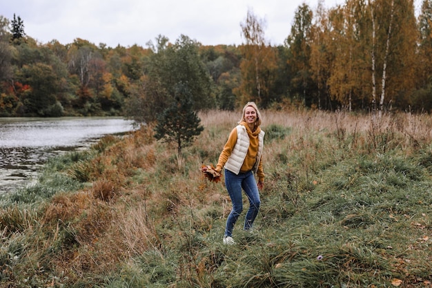 De vrouw is in het herfstpark herfstsfeer schilderachtig uitzicht op de rivier