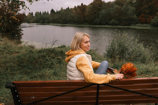 De vrouw is in het herfstpark Herfstsfeer schilderachtig uitzicht op de rivier