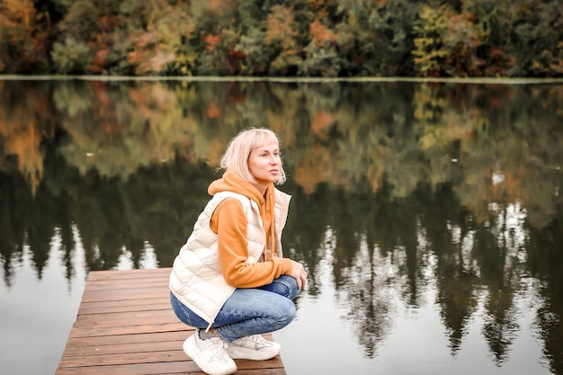 De vrouw is in het herfstpark Herfstsfeer schilderachtig uitzicht op de rivier