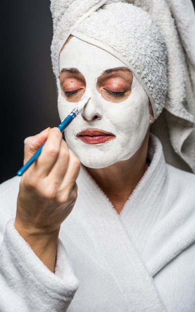 De vrouw is witte klei op zijn gezichtsmasker