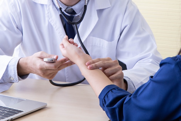 De vrouw kwam naar de dokter. De arts meet de pols van de patiënt.