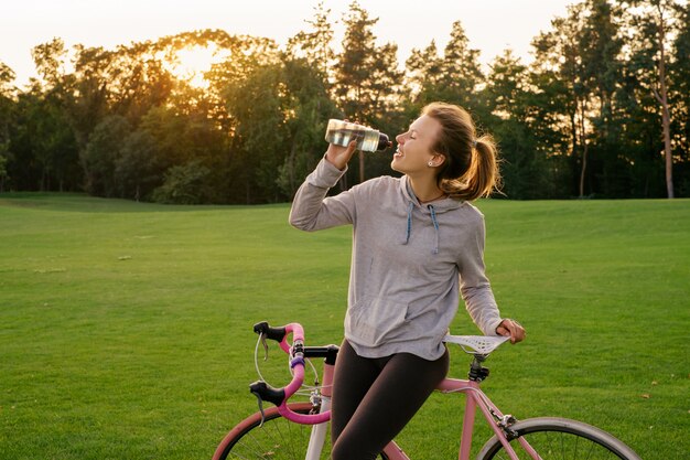 De vrouw lest dorst na het berijden van een fiets