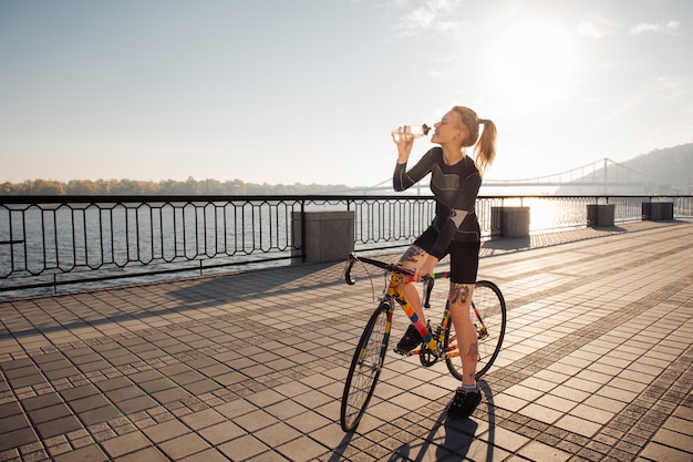 De vrouw lest dorst terwijl het berijden van een fiets