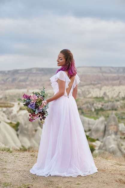 De vrouw met mooi boeket van bloemen in handen bevindt zich op berg in stralen van dageraadzonsondergang