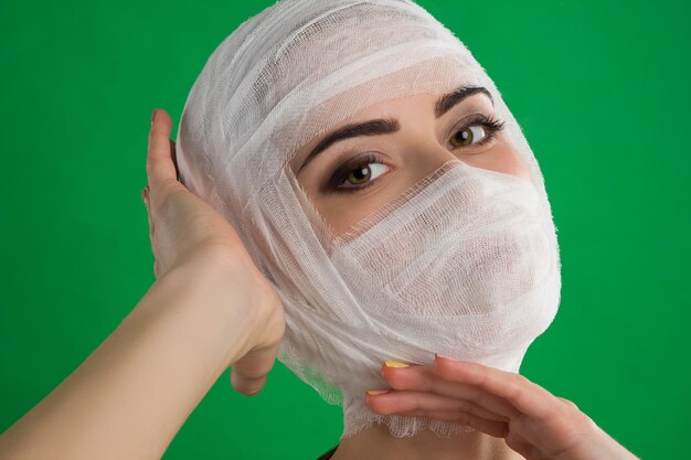 De vrouw met ogen en een verband op haar hoofd poseert tegen de achtergrond van chromakey