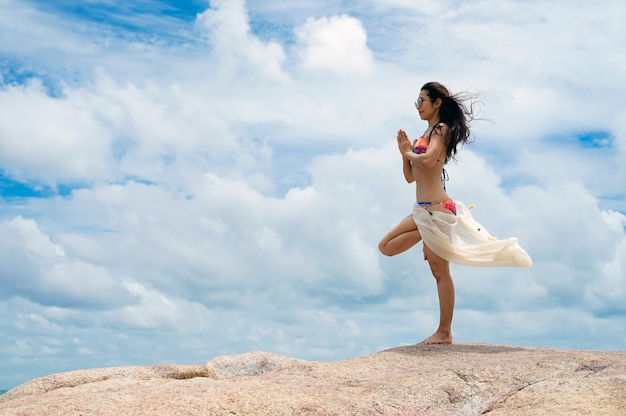 De vrouw met yogahouding op het strand