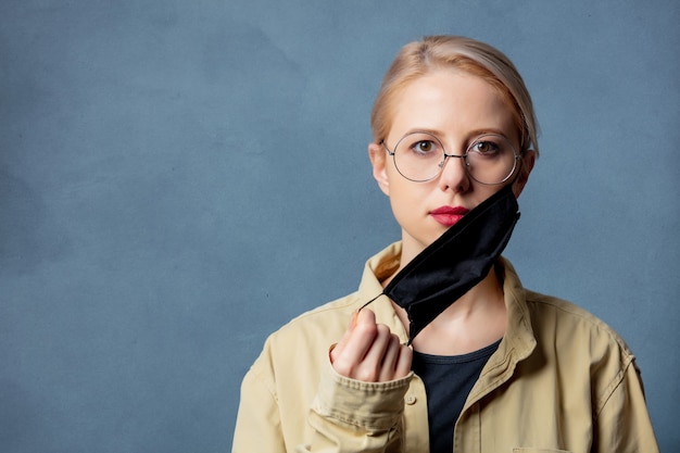 De vrouw neemt een zwart gezichtsmasker op grijze ruimte op