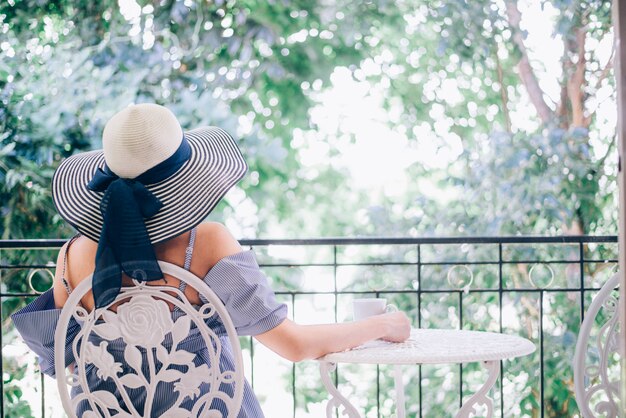 De vrouw ontspant en het drinken koffie en theezonzitting openlucht in zonneschijnlicht genietend van haar ochtendkoffie